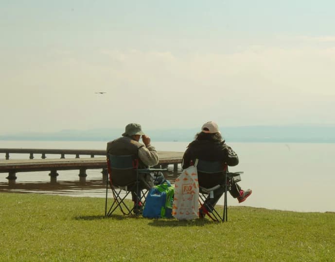 Two birders on a bench watching the water at dusk